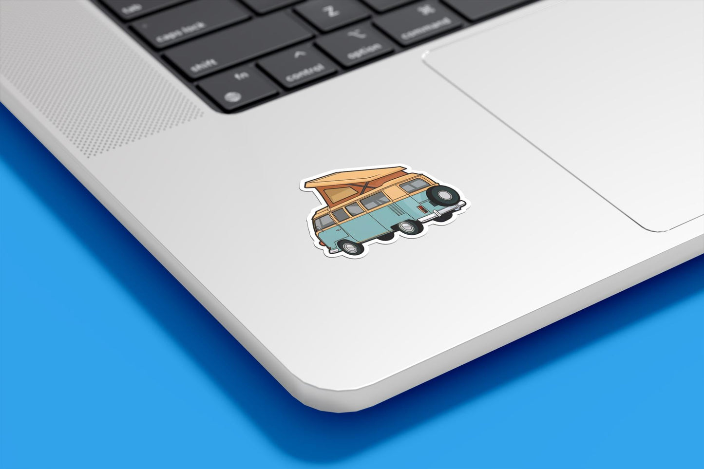 Laptop with a camper van sticker on a blue surface