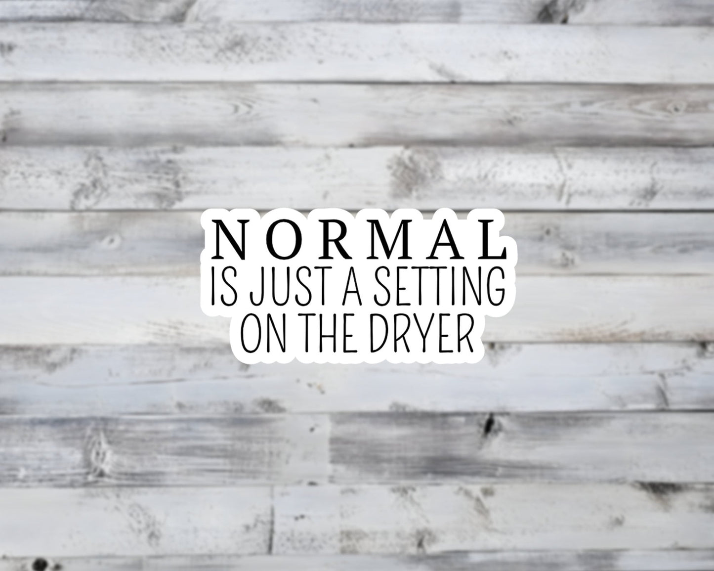 Text 'NORMAL IS JUST A SETTING ON THE DRYER' on a wooden background