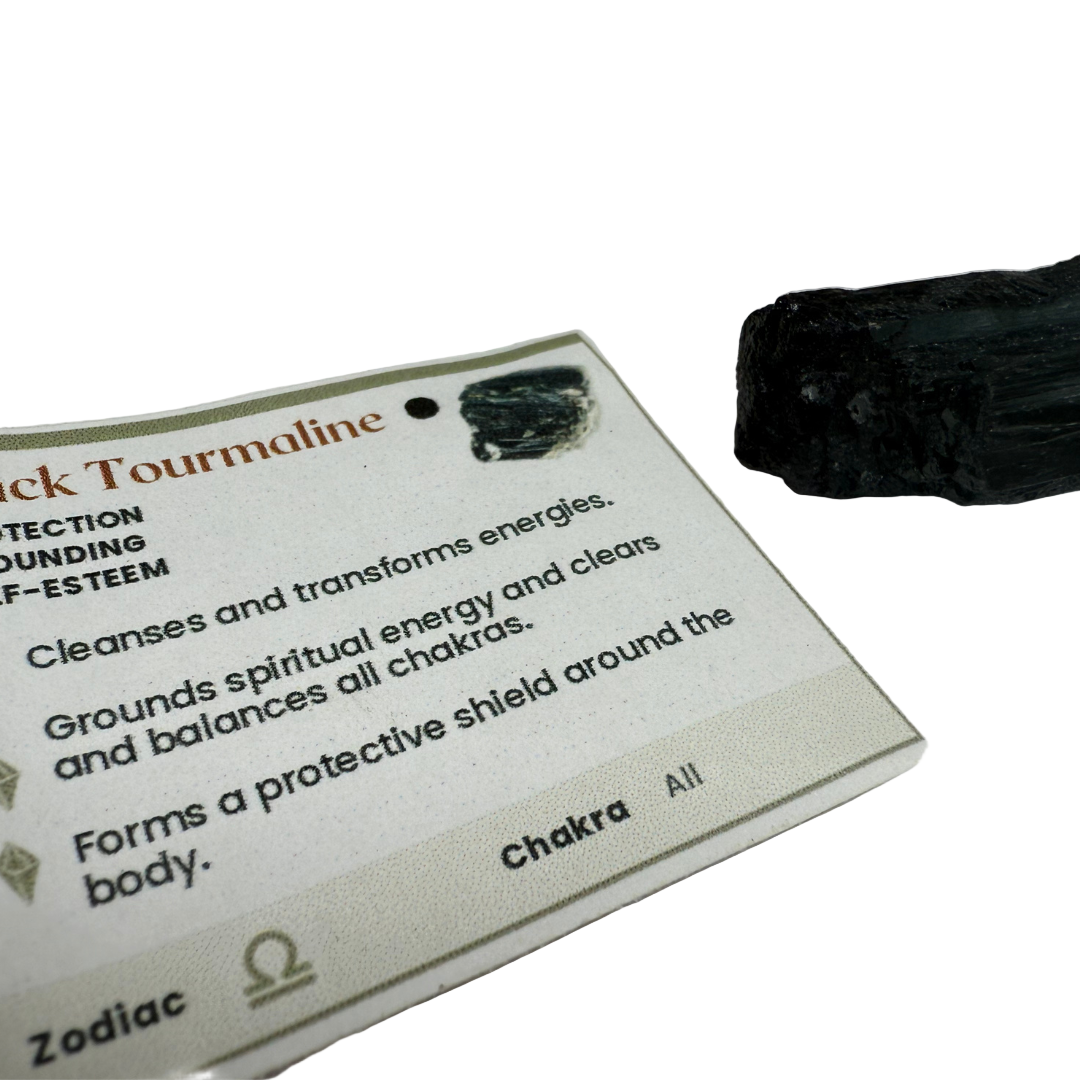 Black tourmaline crystal on a card with information about its properties.
