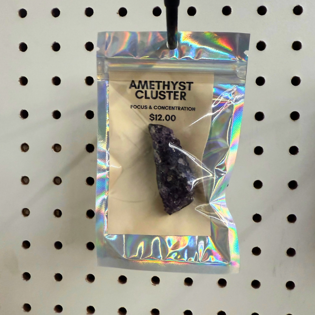 Holographic packaging of an amethyst cluster with product details on a pegboard background