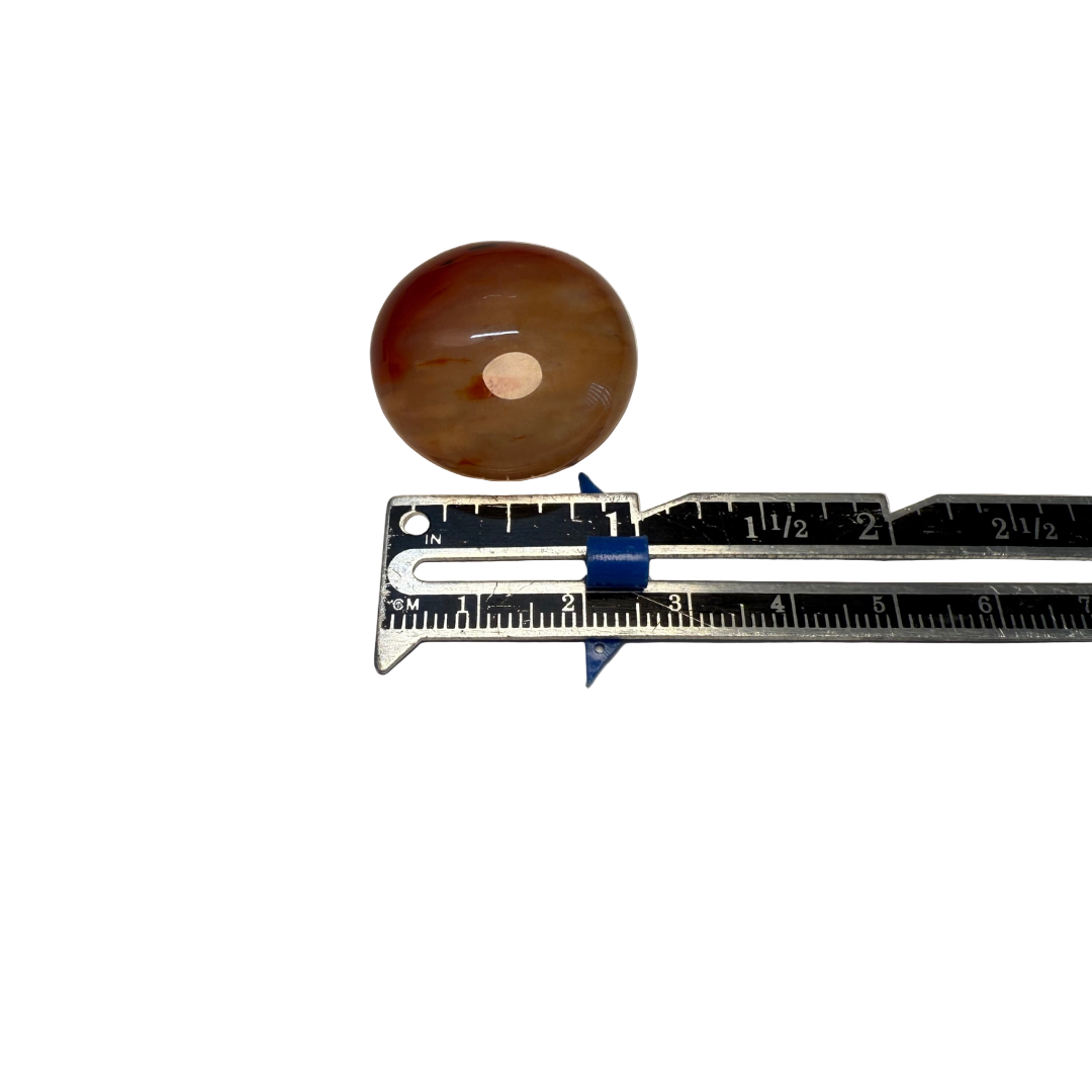 Circular carnelian with a ruler for scale on a gray background