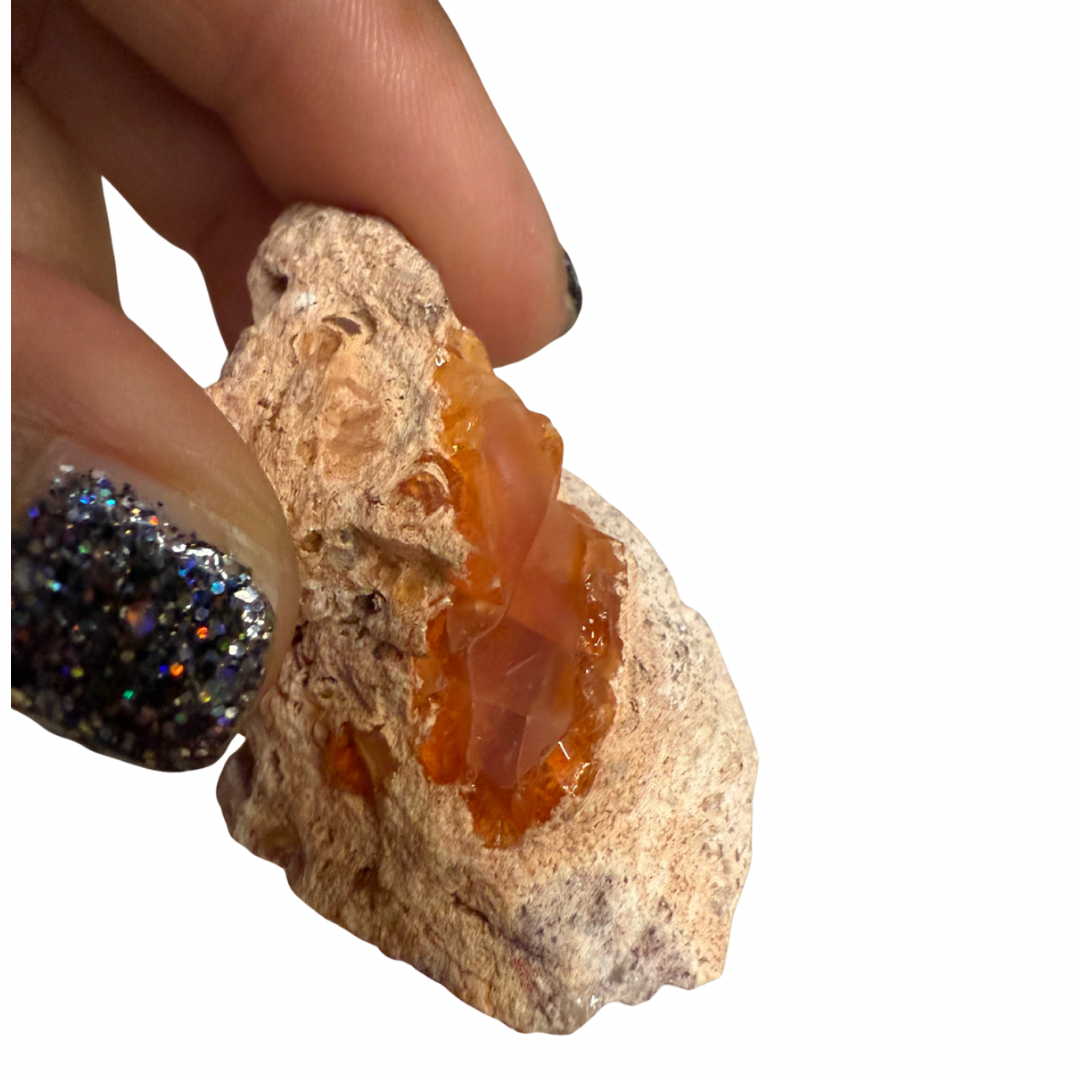Mineral sample held by a hand with a white background