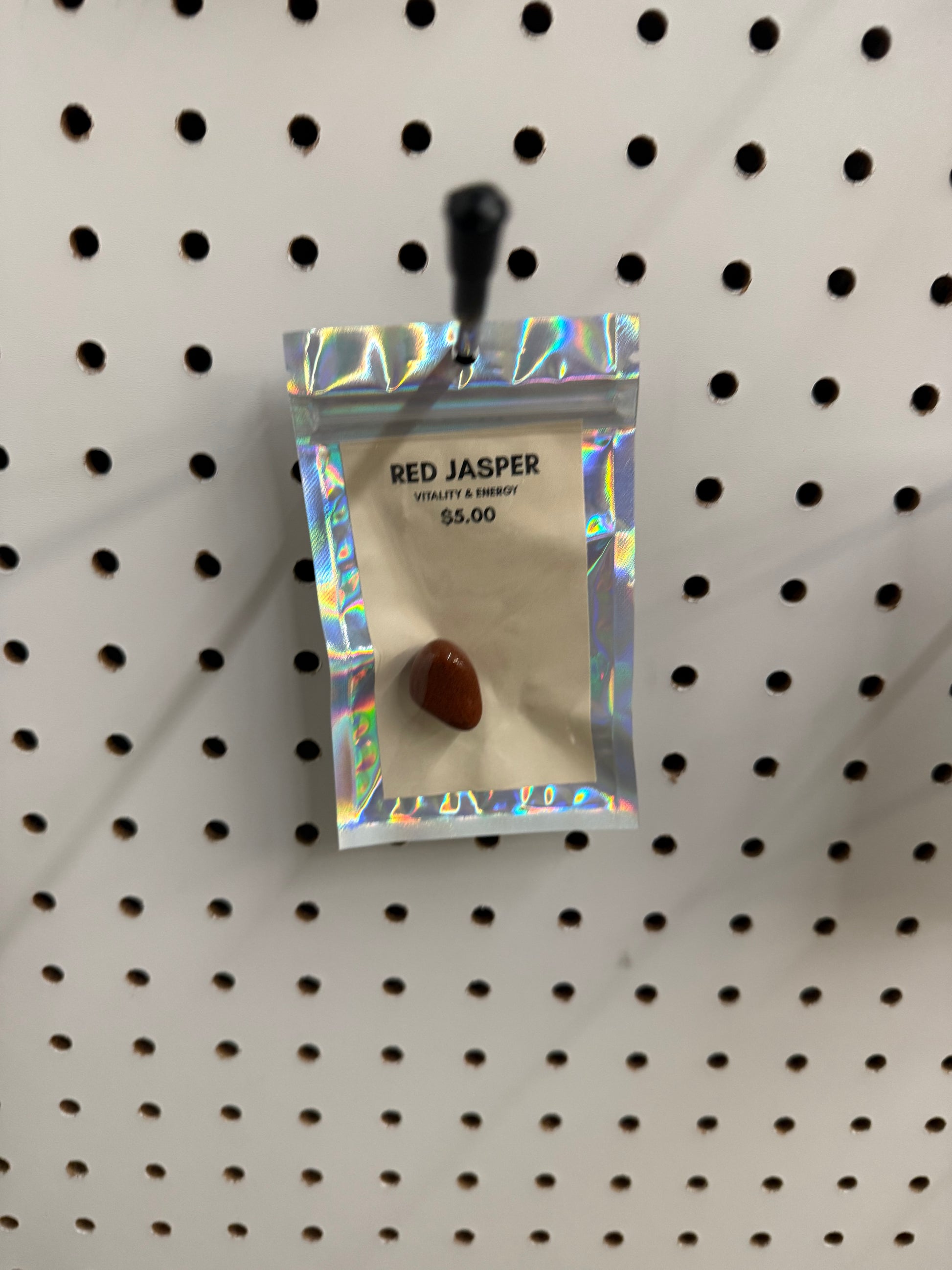 Red Jasper stone in a holographic packaging on a pegboard