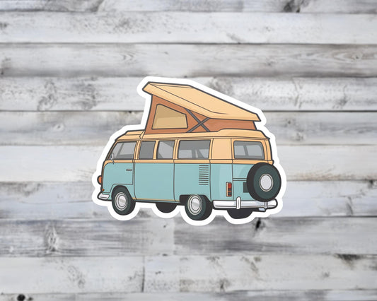 Sticker of a vintage camper van with an open roof on a wooden surface
